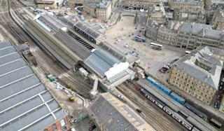 The first section of roof to be restored as part of the wider Huddersfield station upgrade was unveiled in April. With the expansive scaffolding structure now moved so the restoration of the next section can commence. Northern Class 150 waits at the west-facing Penistone Platform 2. This platform will be moved closer to the main entrance to improve accessibility. CHRIS HOWE.