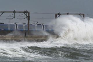 Waves crash over a ScotRail train where the line skirts the Firth of Clyde at Saltcoats.