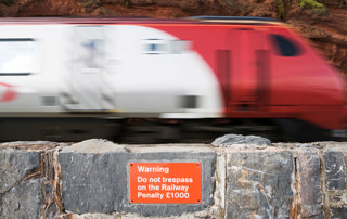 Do not trespass sign on siding with train passing it at speed