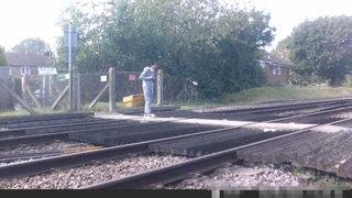 CCTV still of a pedestrian distracted by a mobile phone whilst on a level crossing. NETWORK RAIL.