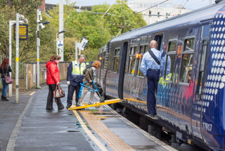 A passenger, assisted by staff, uses the disabled ramp to board a ScotRail train at Partick station. ALAMY.
