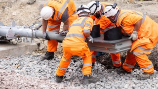 Rail engineers lift a new signal into place