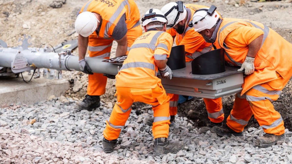 Rail engineers lift a new signal into place